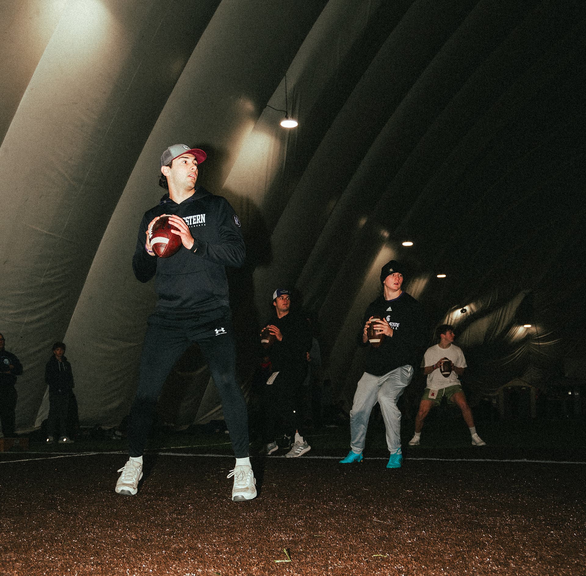 Three quarterbacks at QB Era are dropping back together during a drill looking downfield at potential receivers