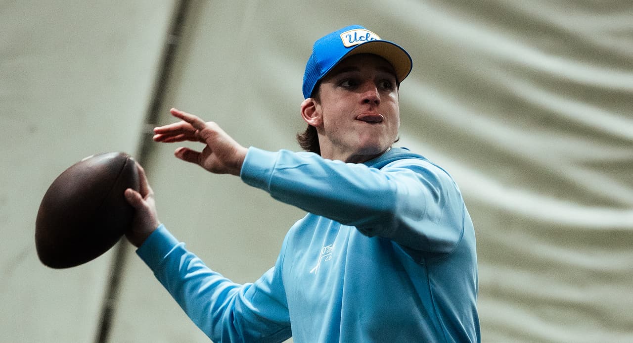 Colton Gumino holding a football looking downfield at training